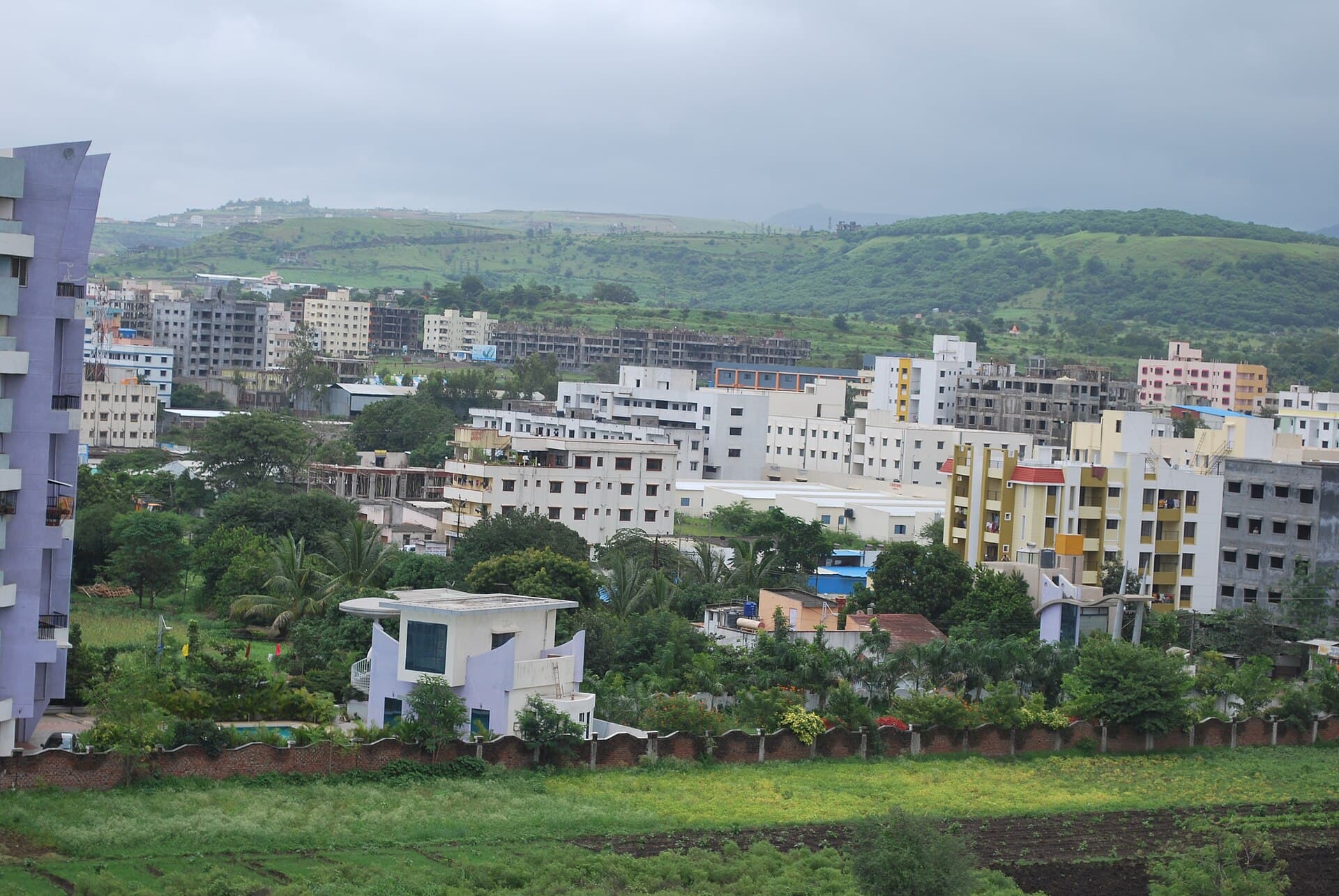 Apartment buildings and houses in Dhayri, Pune, with hills behind